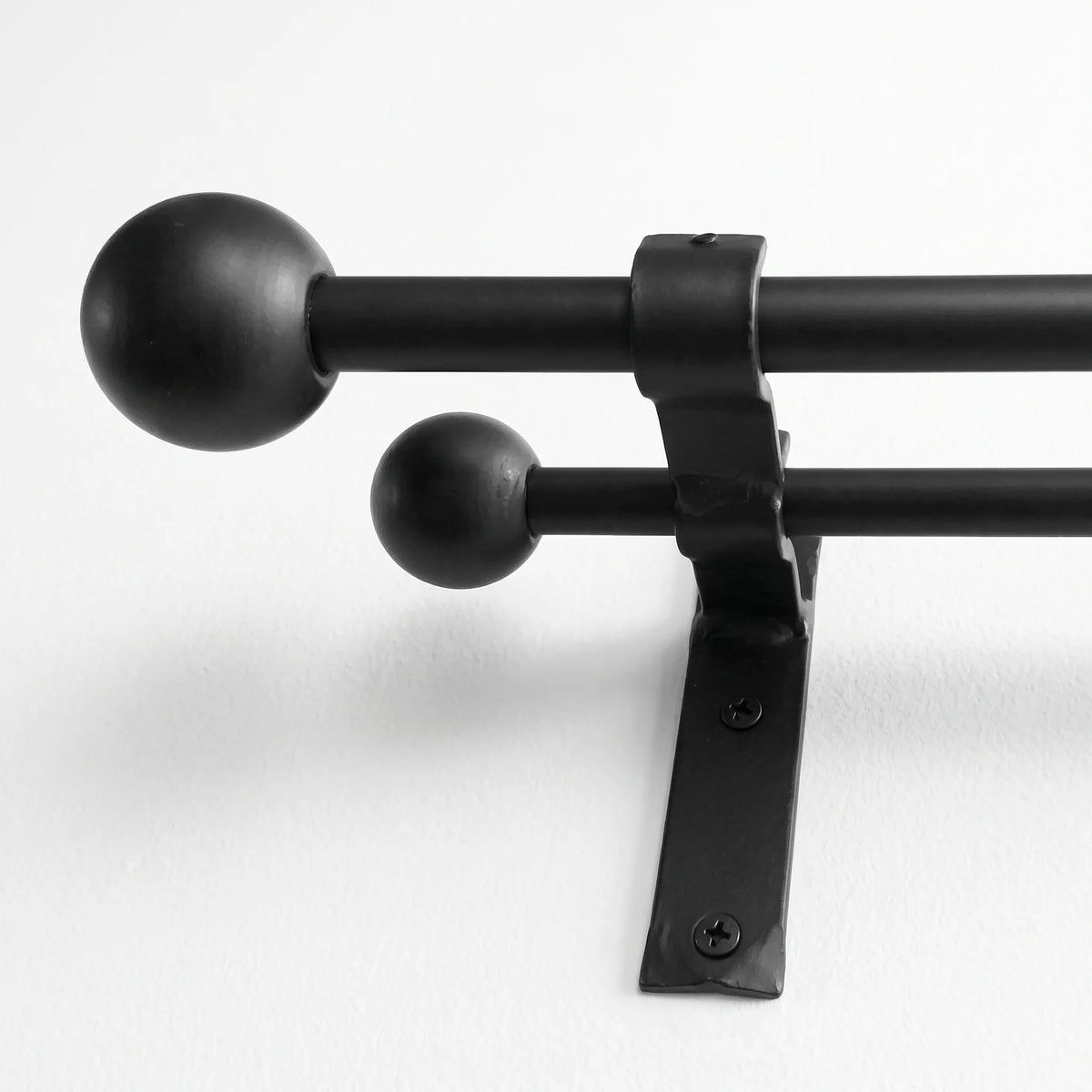 Wrought iron curtain pole hanging on wall in white finish