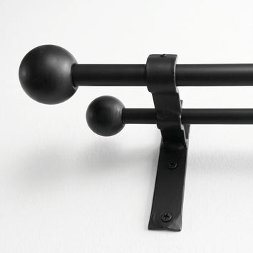 Wrought iron curtain pole hanging on wall in white finish